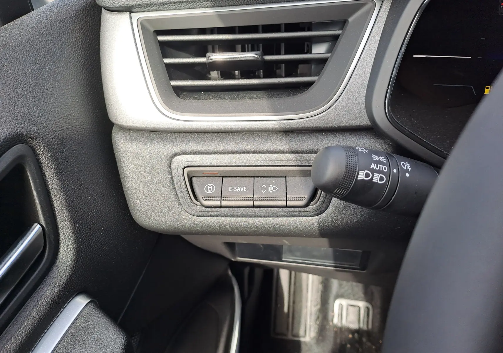 Gros plan sur la commande d'éclairage et la ventilation côté gauche du tableau de bord du Renault Captur 2025 hybride.