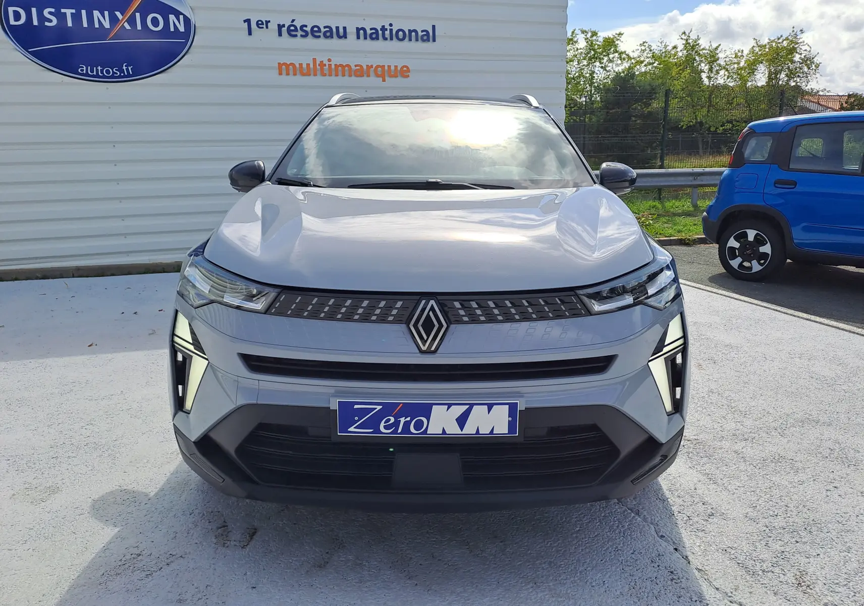 Vue frontale d'un Renault Captur gris Rafale métal avec toit noir, éclairage LED distinctif et plaque Zéro KM.