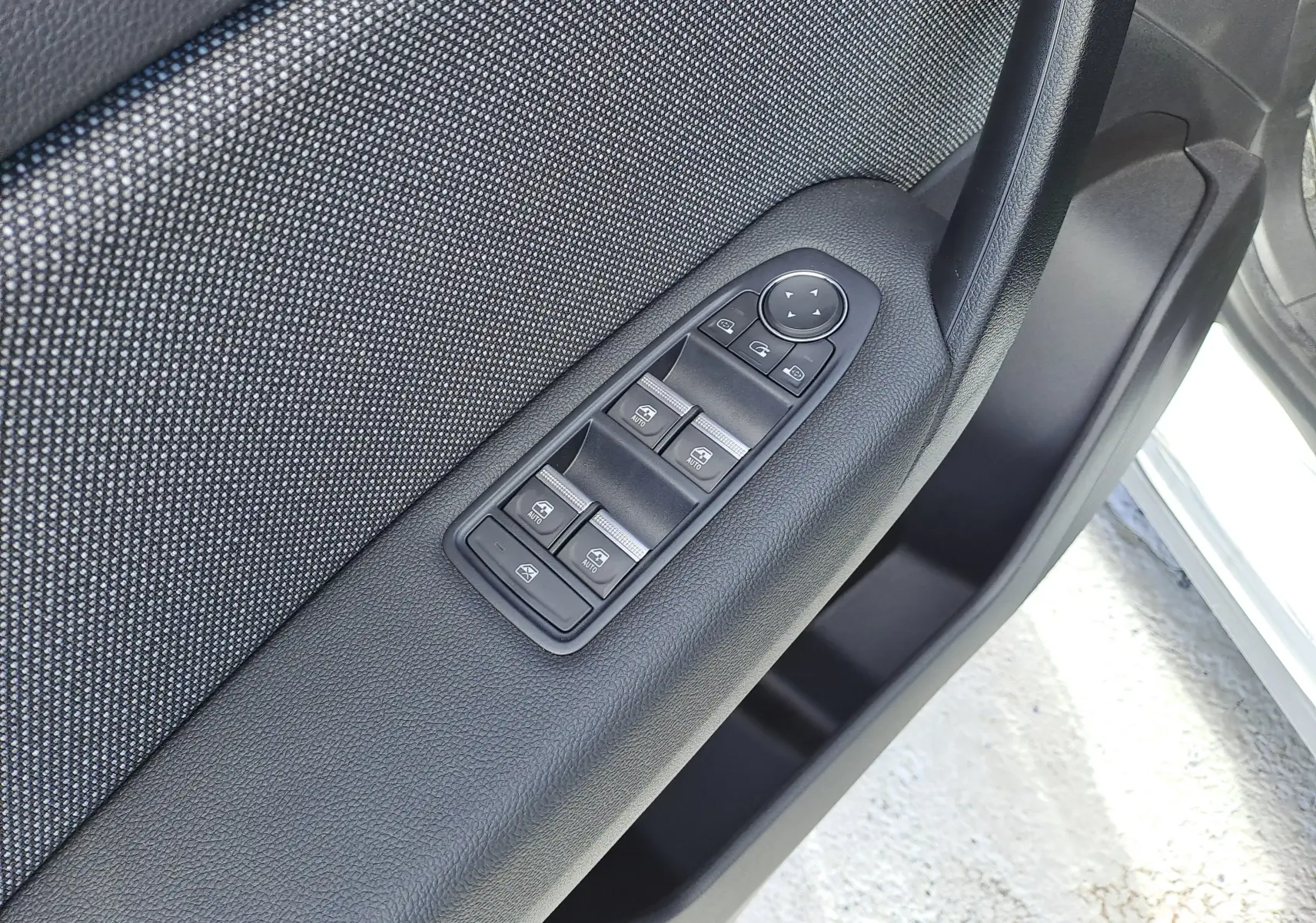 Gros plan sur les commandes des vitres et rétroviseurs côté conducteur du Renault Captur gris Rafale métal 2025.
