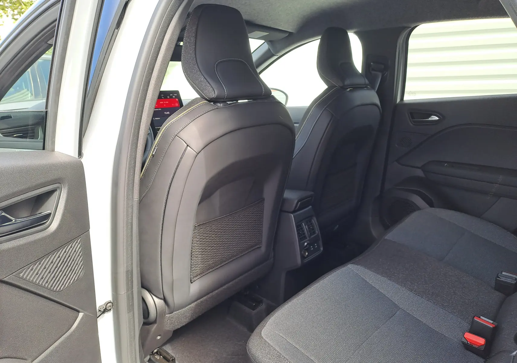 Vue intérieure arrière côté gauche du Renault Captur 2025, sièges tissu gris et dossier cuir noir avec surpiqûres.