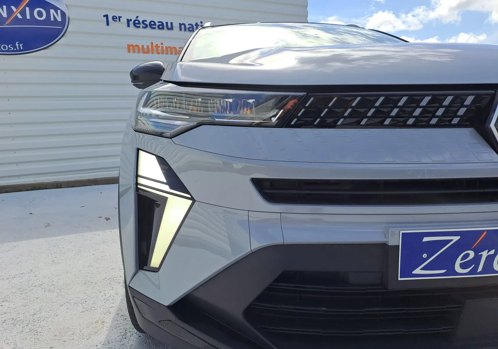 Gros plan sur l'avant gauche du Renault Captur 2025 gris rafale métal avec feux LED distinctifs et calandre noire.