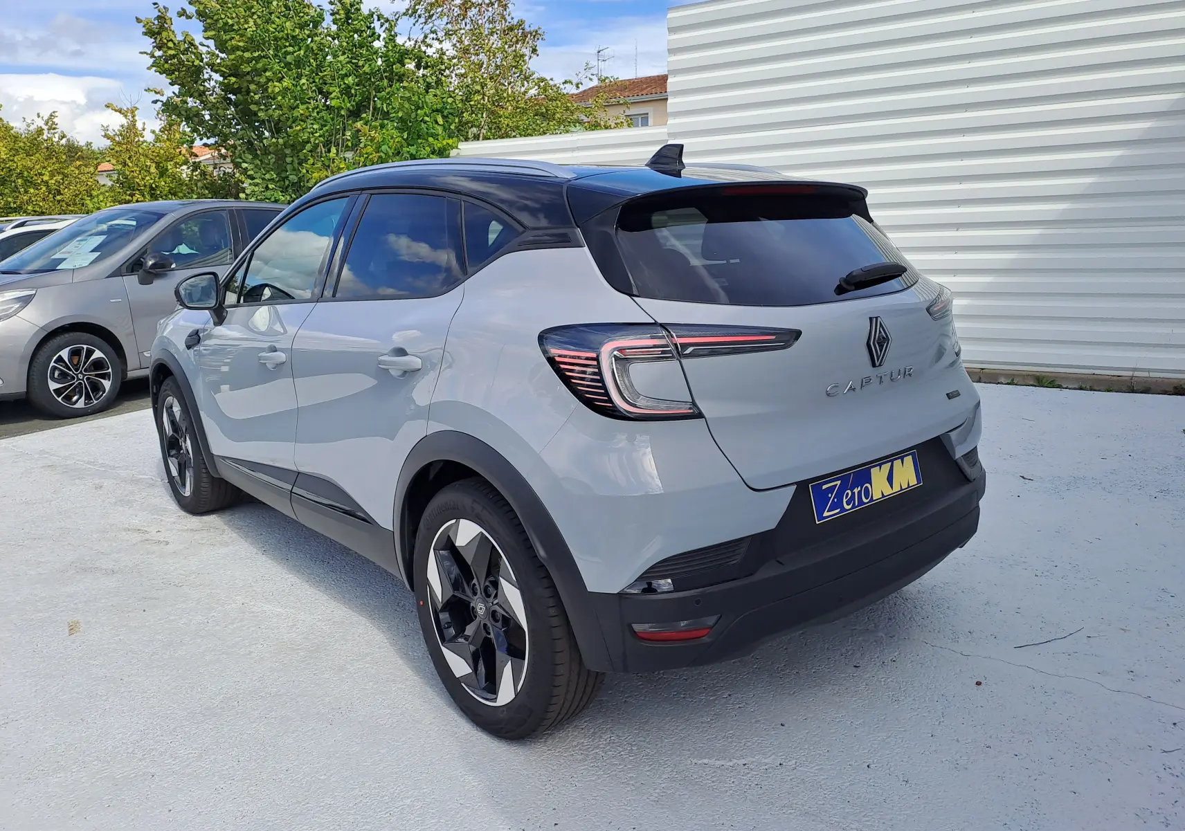 Vue 3/4 arrière droite du Renault Captur 2025 gris Rafale métal avec toit noir et feux arrière LED distinctifs.
