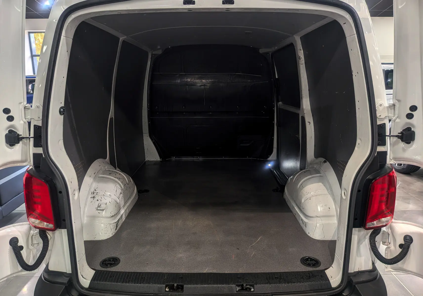 Vue arrière ouverte du Volkswagen Transporter 6.1 Van blanc Candy montrant l'espace de chargement vide et les parois noires.
