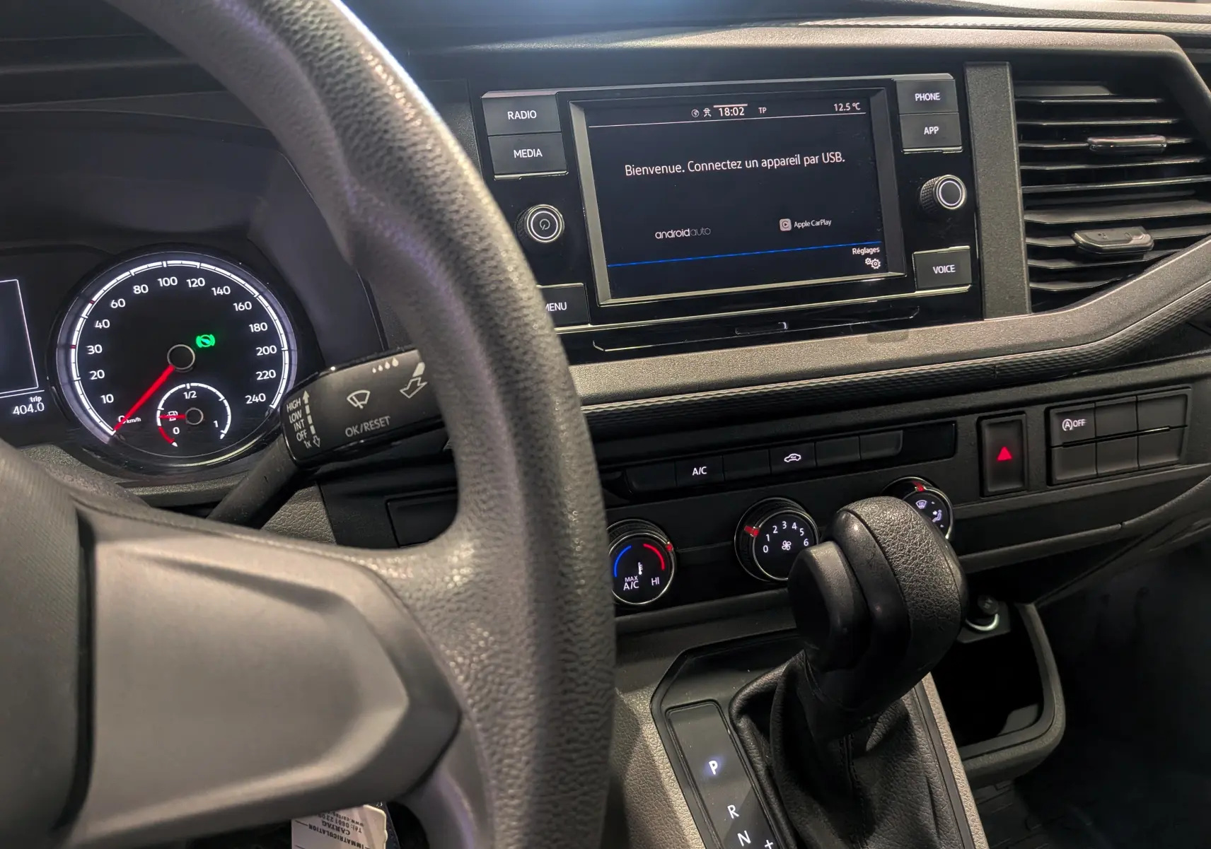 Vue intérieure du tableau de bord du Volkswagen Transporter 6.1 blanc, avec écran tactile et levier de vitesses automatique.