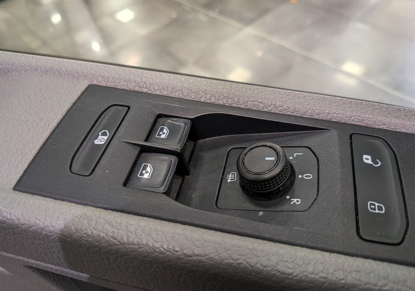 Gros plan sur les commandes de porte côté conducteur du Volkswagen Transporter 6.1 blanc, avec boutons de vitres et réglage des rétroviseurs.