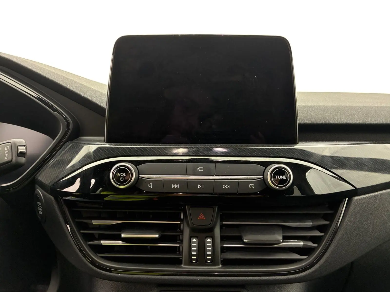 Vue rapprochée du tableau de bord du Ford Kuga 2024, écran tactile éteint et commandes audio noires brillantes.