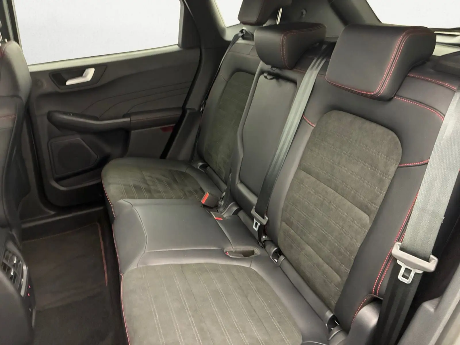 Vue intérieure des sièges arrière en cuir noir avec surpiqûres rouges du Ford Kuga 2024, version hybride.