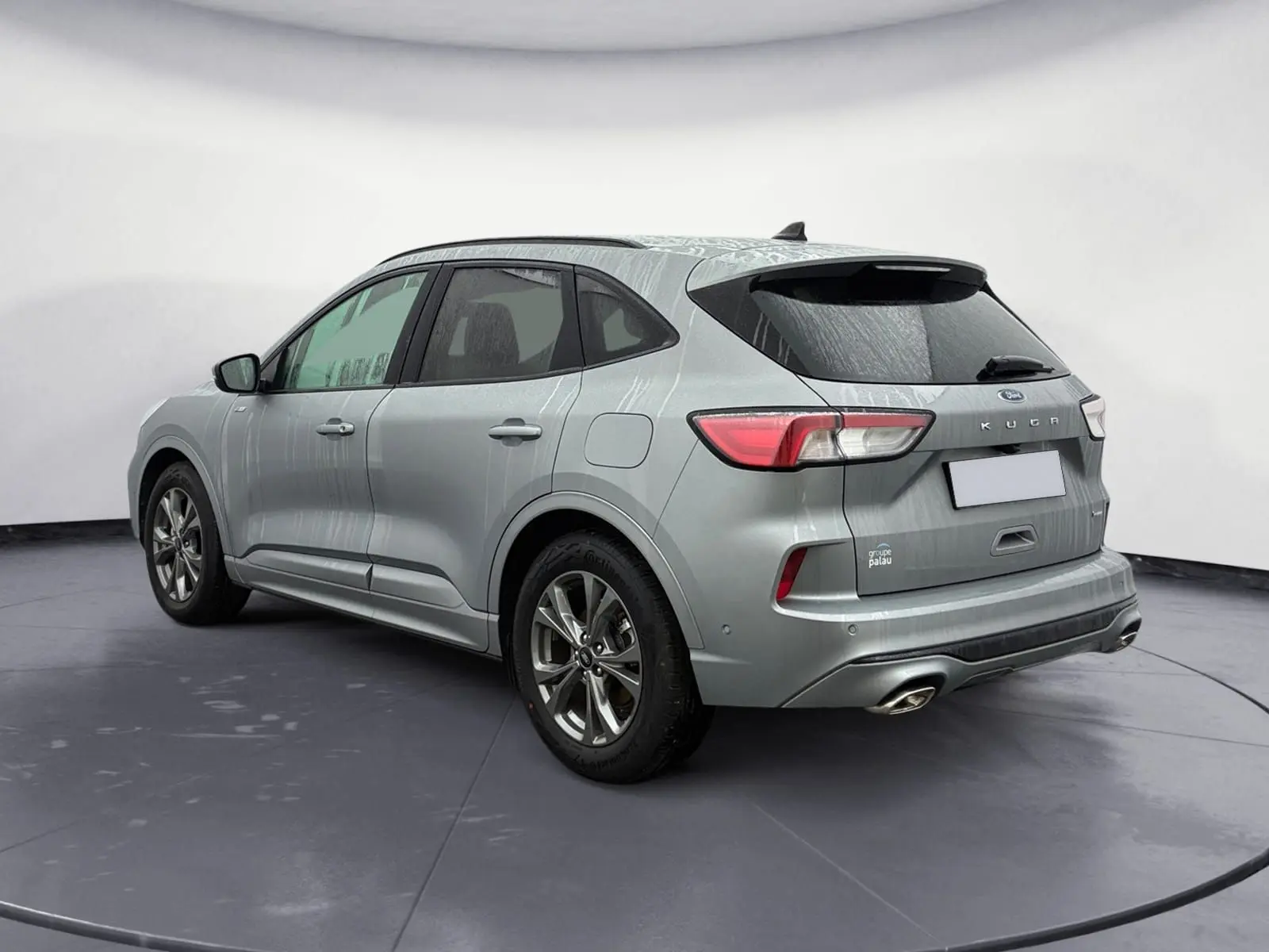 Vue 3/4 arrière droite d’un Ford Kuga gris 2024 hybride essence, finition ST-Line X avec double sortie d’échappement.