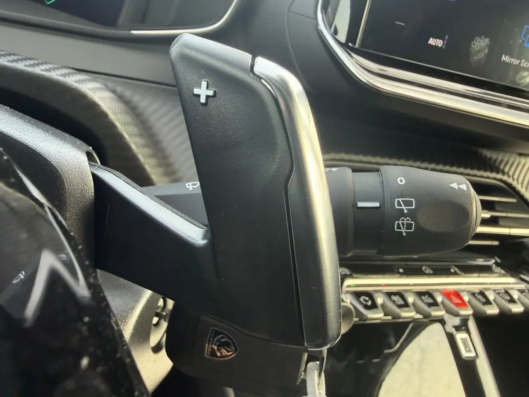 Gros plan sur la commande de palette de changement de vitesse côté droit dans l’habitacle gris de la Peugeot 208 Hybrid 110 e-DCS6 Allure.