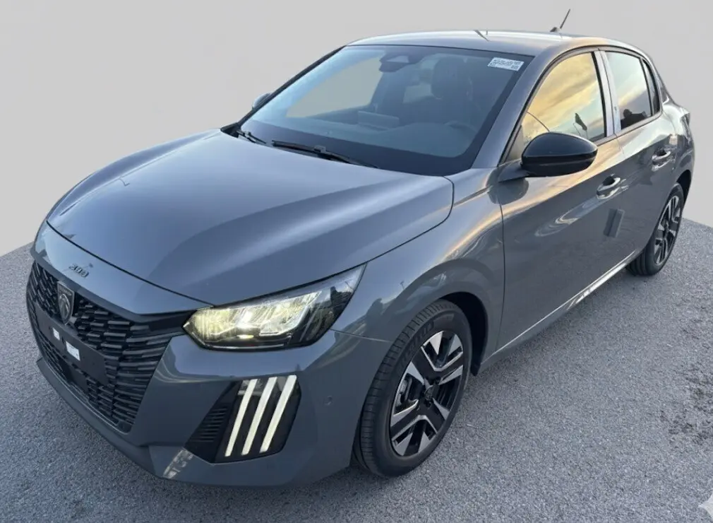 Peugeot 208 Hybrid gris vue 3/4 avant droit, avec feux allumés et jantes alliage noires et argentées.
