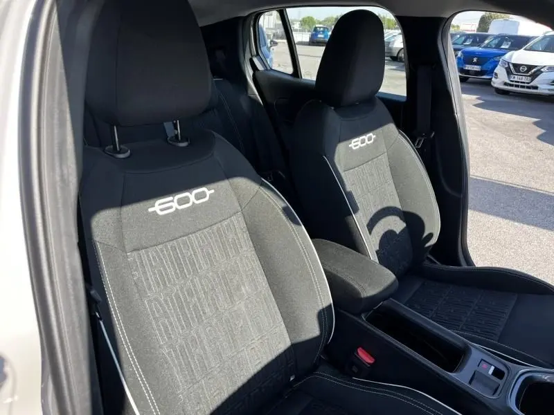Vue intérieure rapprochée des sièges avant noirs avec logo 600, dans une FIAT 600 beige 2025 côté conducteur.