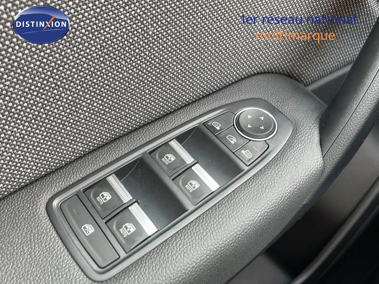 Gros plan sur les commandes des vitres électriques côté gauche d'un Renault Captur gris cassiopée métal avec toit noir.