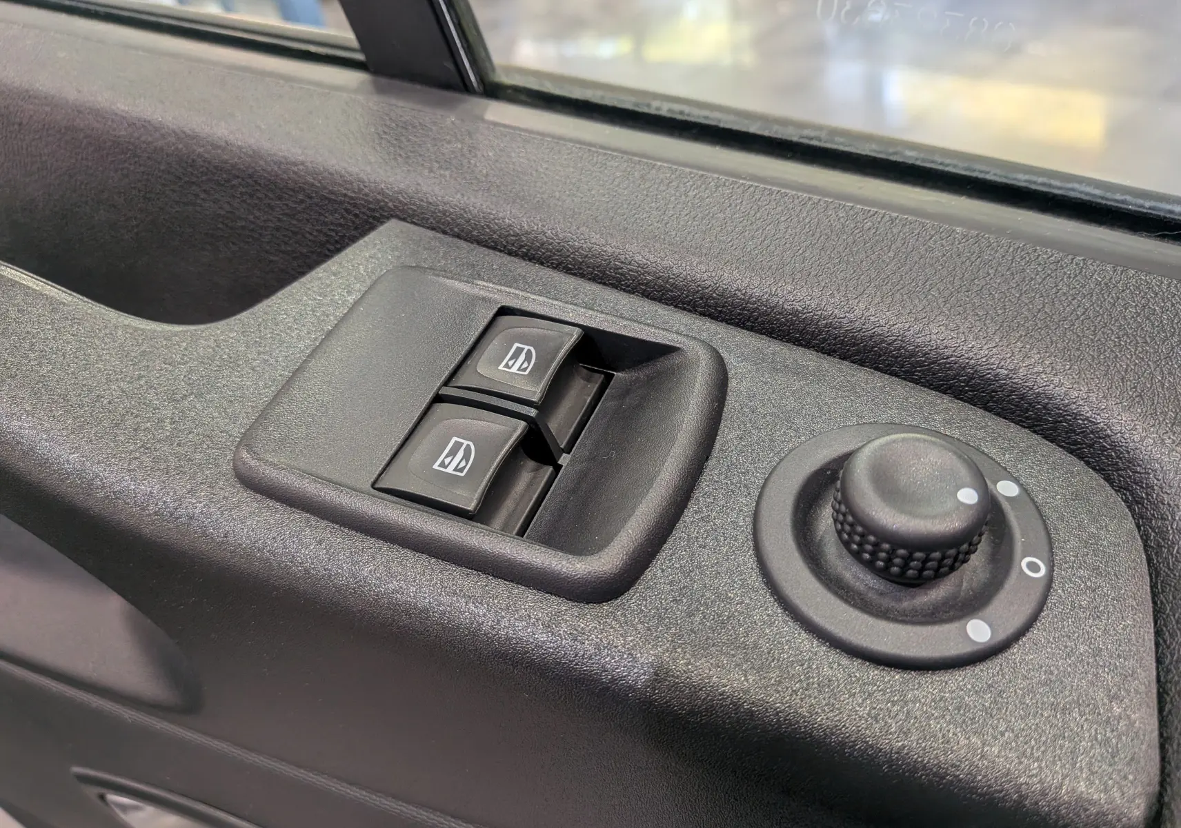 Commande des vitres électriques et réglage des rétroviseurs sur la portière côté conducteur d'un Renault Trafic blanc.