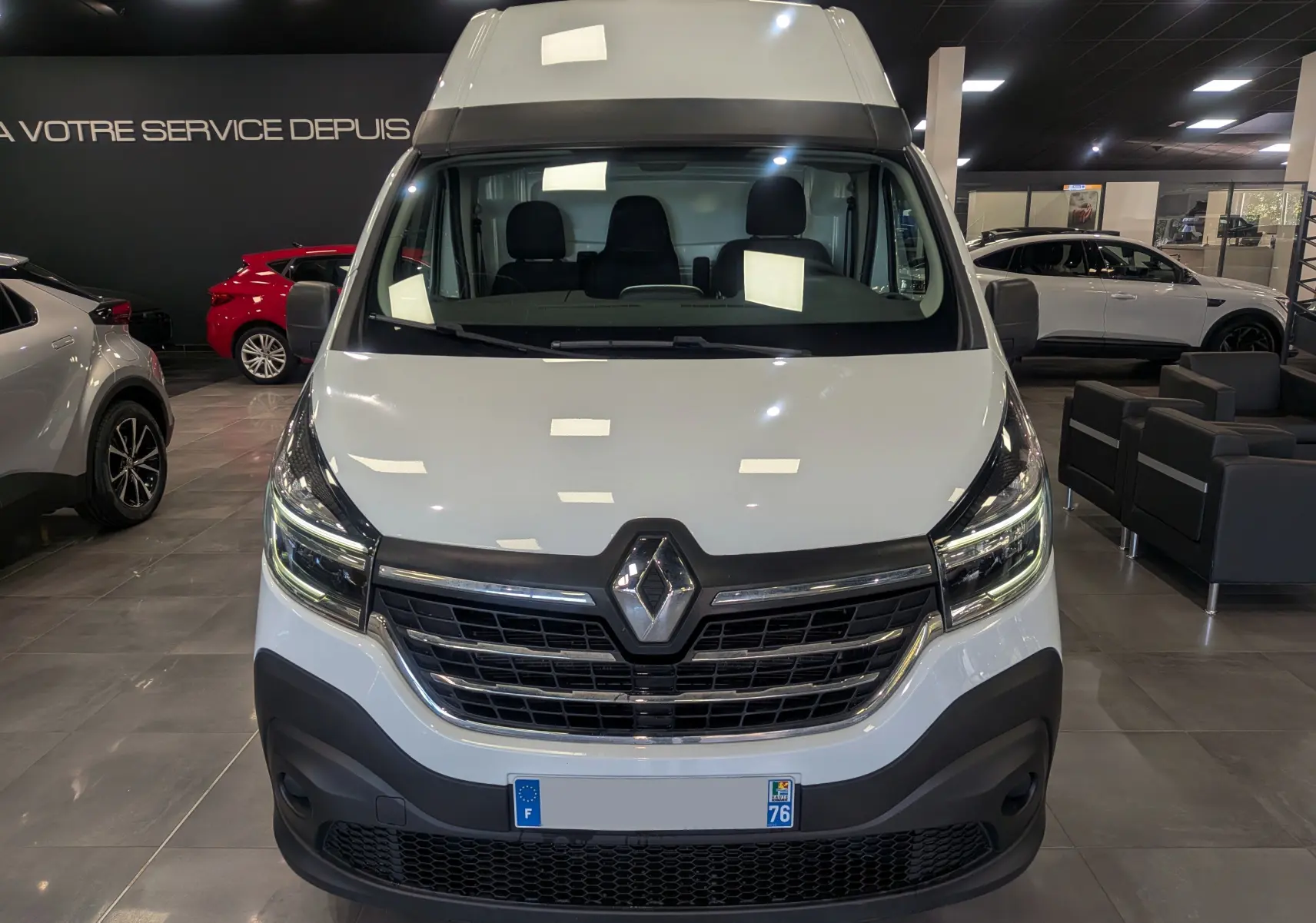 Vue frontale d'un Renault Trafic Fourgon blanc glacier L2H2 2021 en showroom, avec calandre noire et logo Renault visible.