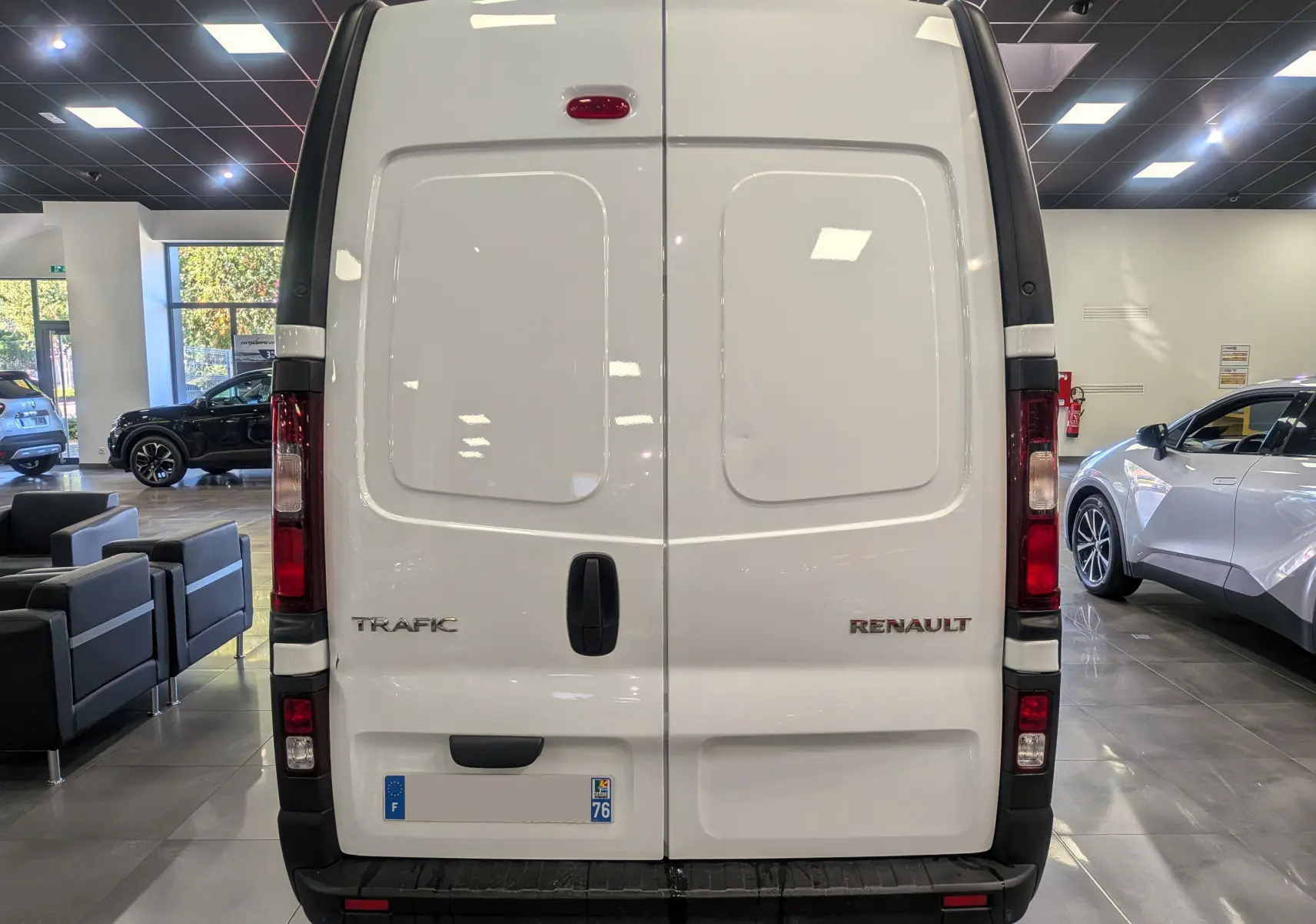 Vue arrière du Renault Trafic Fourgon blanc Glacier L2H2, portes battantes fermées en showroom lumineux.