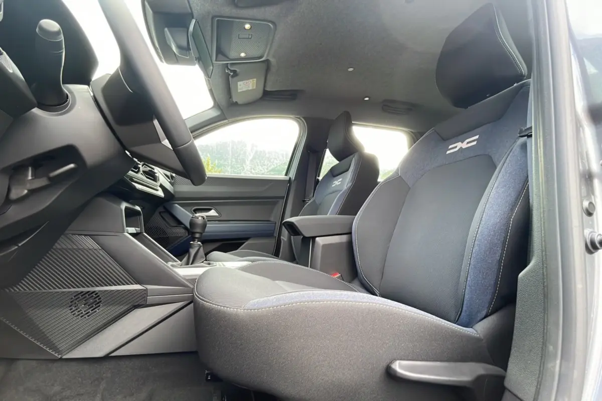 Intérieur avant du Dacia Bigster gris schiste, sièges tissu avec logo DC et levier de vitesses manuel visible.