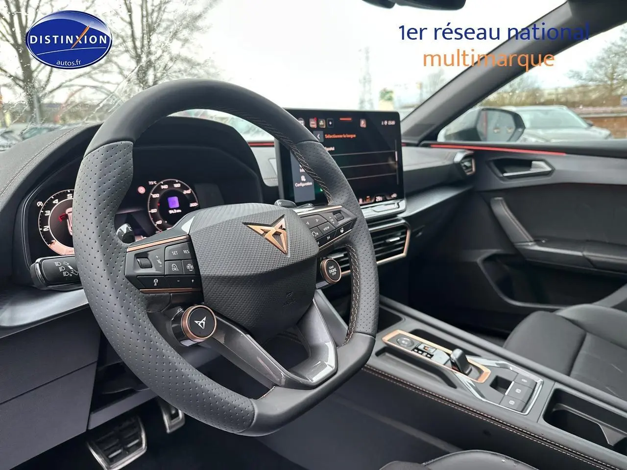 Intérieur de la CUPRA LEON ST 2025, vue côté conducteur sur volant cuir perforé et écran tactile central.