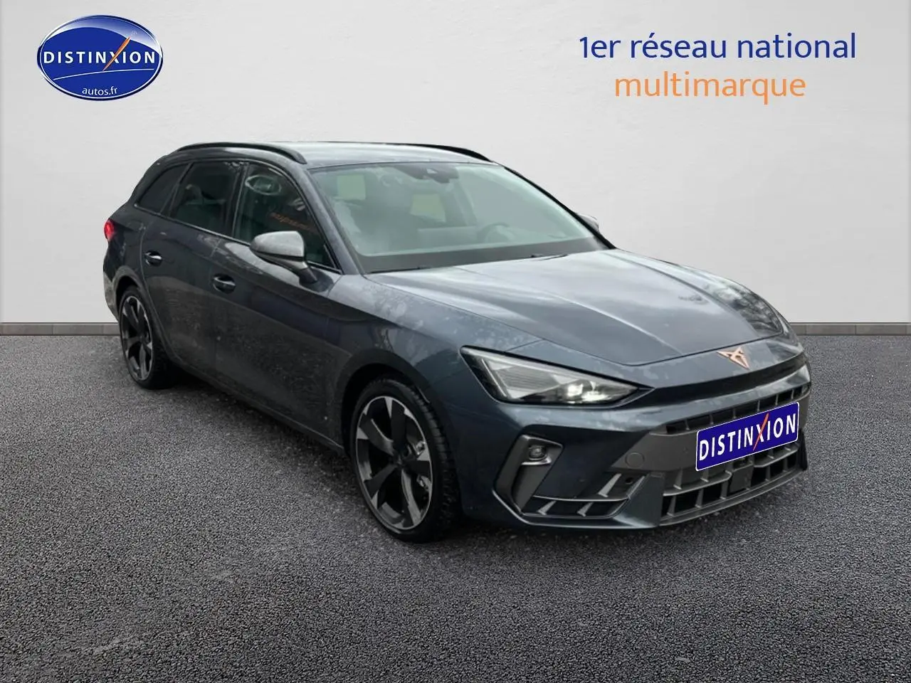 Vue 3/4 avant d'une CUPRA Leon ST 2025 gris magnétique avec jantes alu noires et barres de toit visibles.