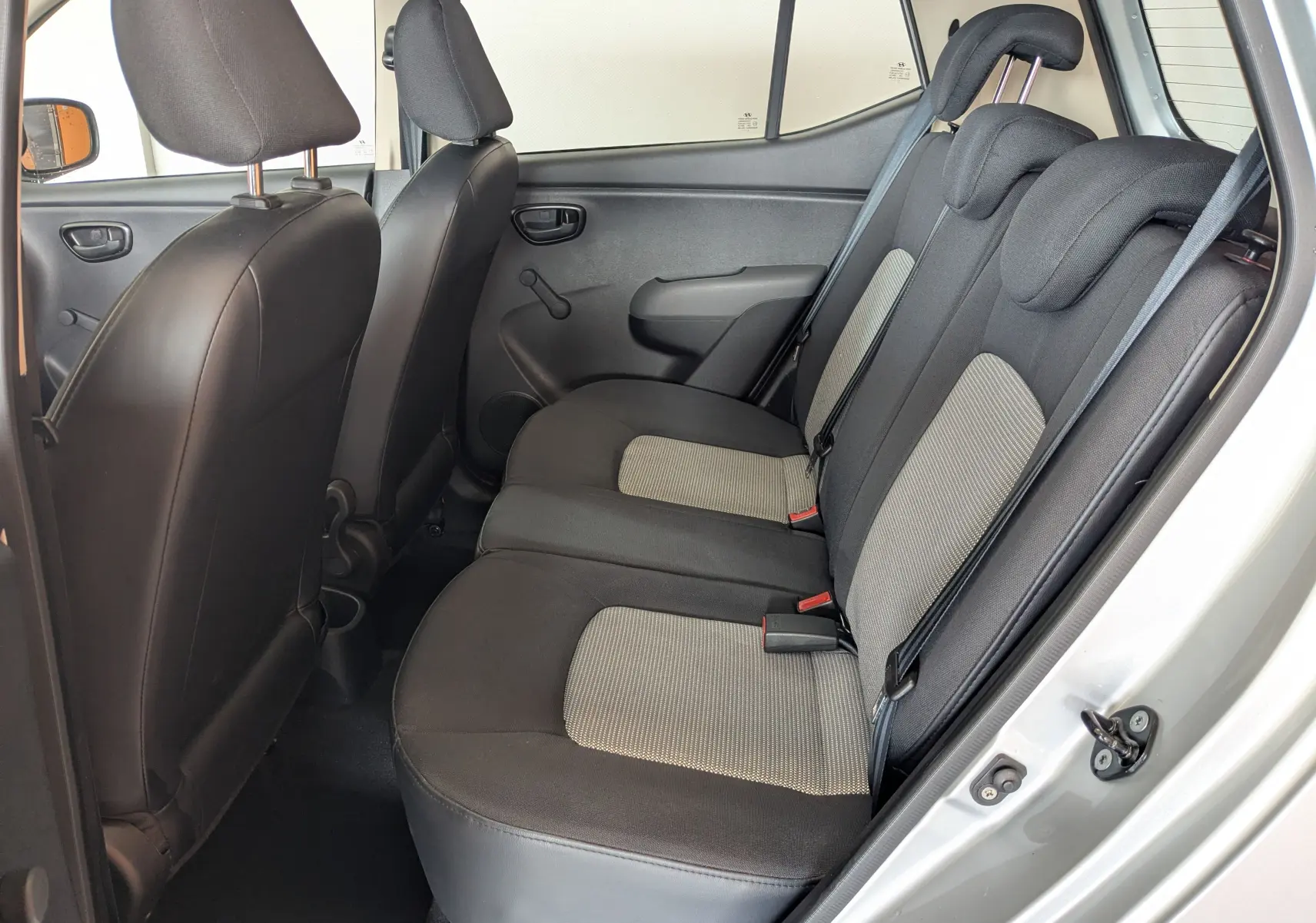 Vue intérieure côté droit des sièges arrière en tissu gris et noir d'une Hyundai i10 gris clair 2010 à 5 portes.