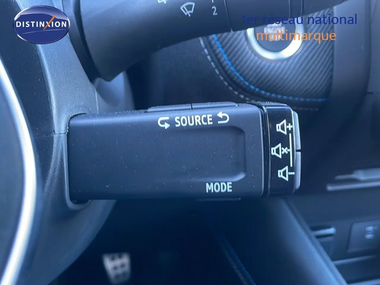 Gros plan sur la commande au volant noire avec inscriptions blanches "SOURCE" et "MODE" dans un Renault Symbioz 2025.