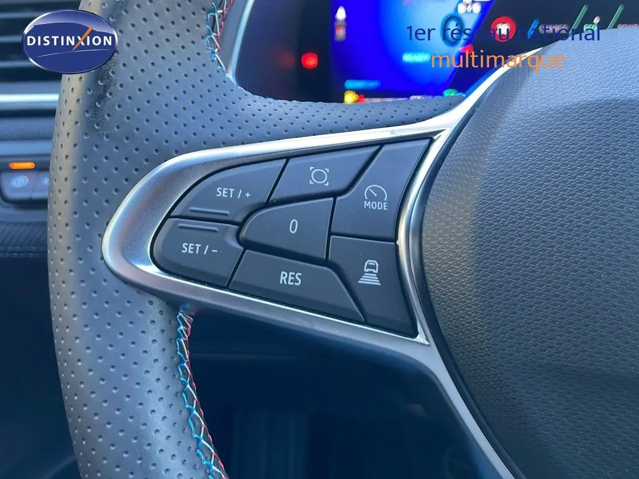 Gros plan sur les commandes au volant en cuir perforé bleu iron metal du Renault Symbioz hybride 2025.