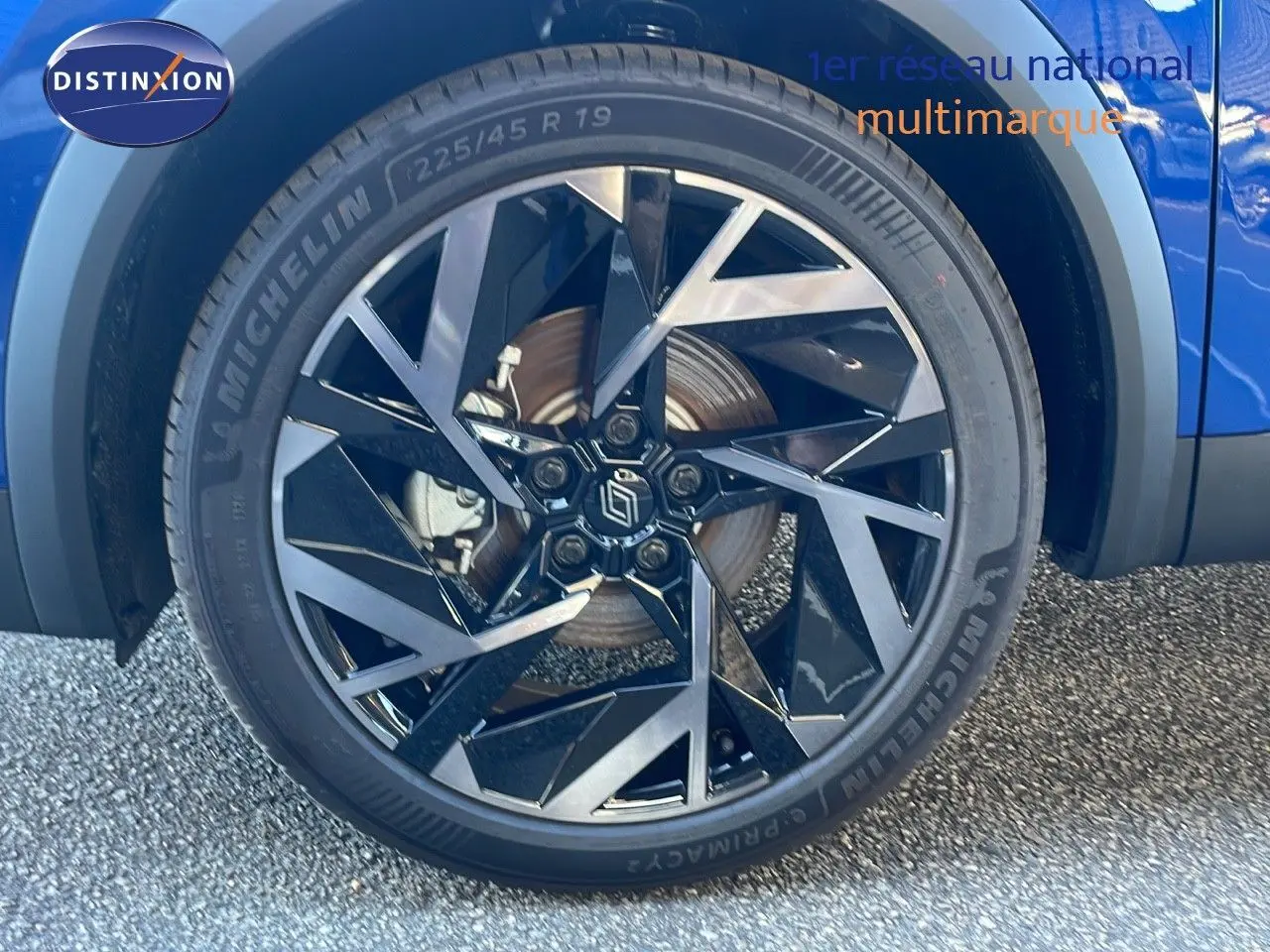 Gros plan sur la roue avant droite bleu iron metal d’une Renault Symbioz 1.6 E-Tech hybride avec jante noire et argentée.