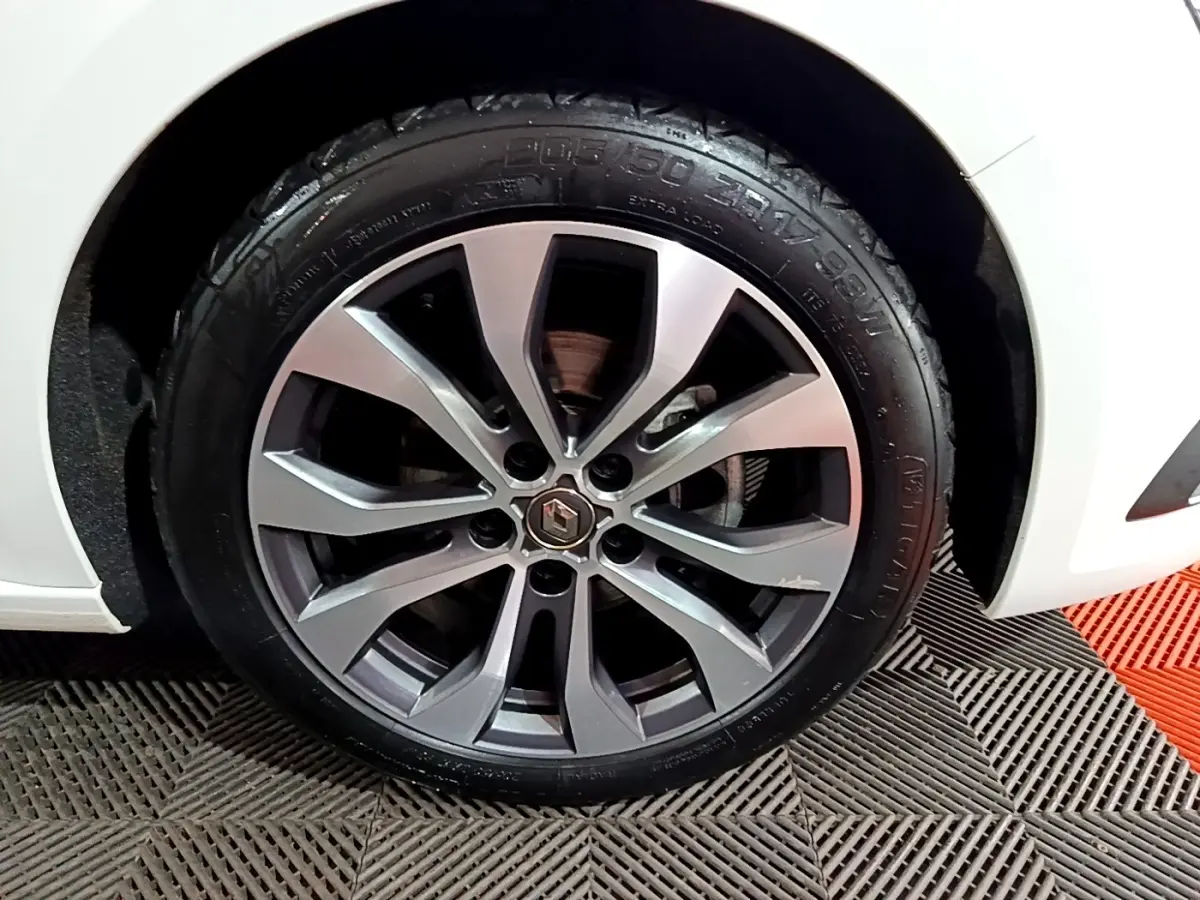 Gros plan sur la roue avant gauche de la Renault Mégane blanche 2023 avec jante alliage à plusieurs branches.