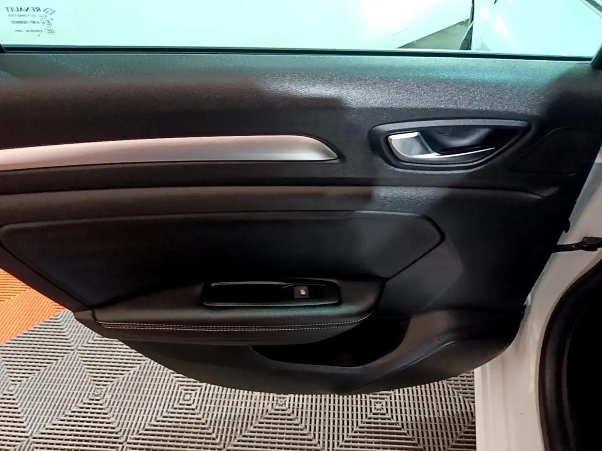 Vue rapprochée de la porte avant droite noire avec poignée argentée d’une Renault Mégane blanche 2023.
