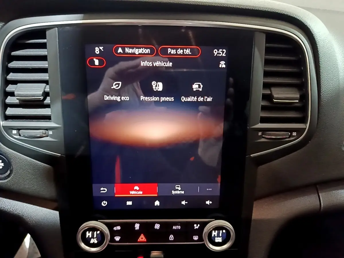 Vue rapprochée du tableau de bord central tactile noir de la Renault Mégane blanche 2023, affichant les infos véhicule.