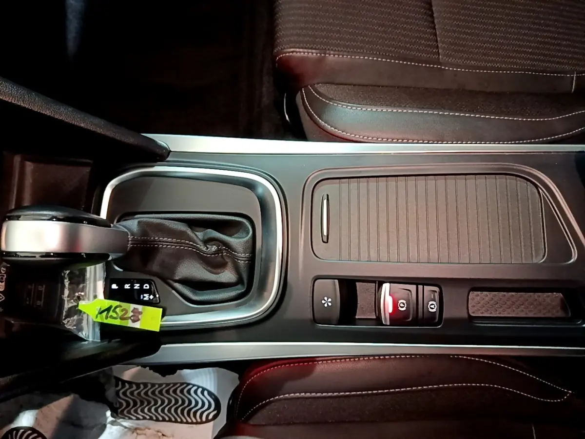 Vue plongeante sur la console centrale noire de la Renault Mégane Techno TCe 140 EDC 2023 avec levier de boîte auto et sièges en tissu.