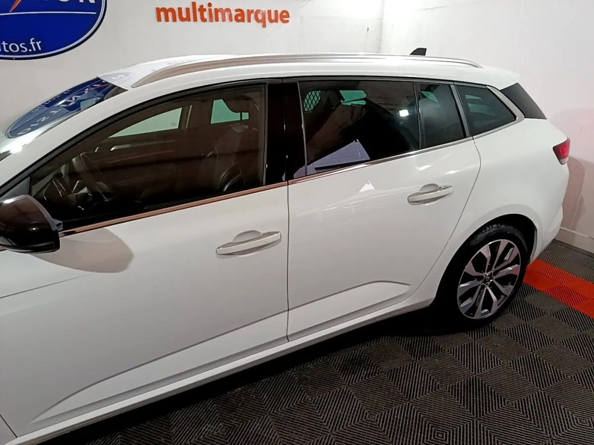 Vue de profil côté gauche d'une Renault Mégane blanche 2023 avec jantes alliage et vitres teintées.