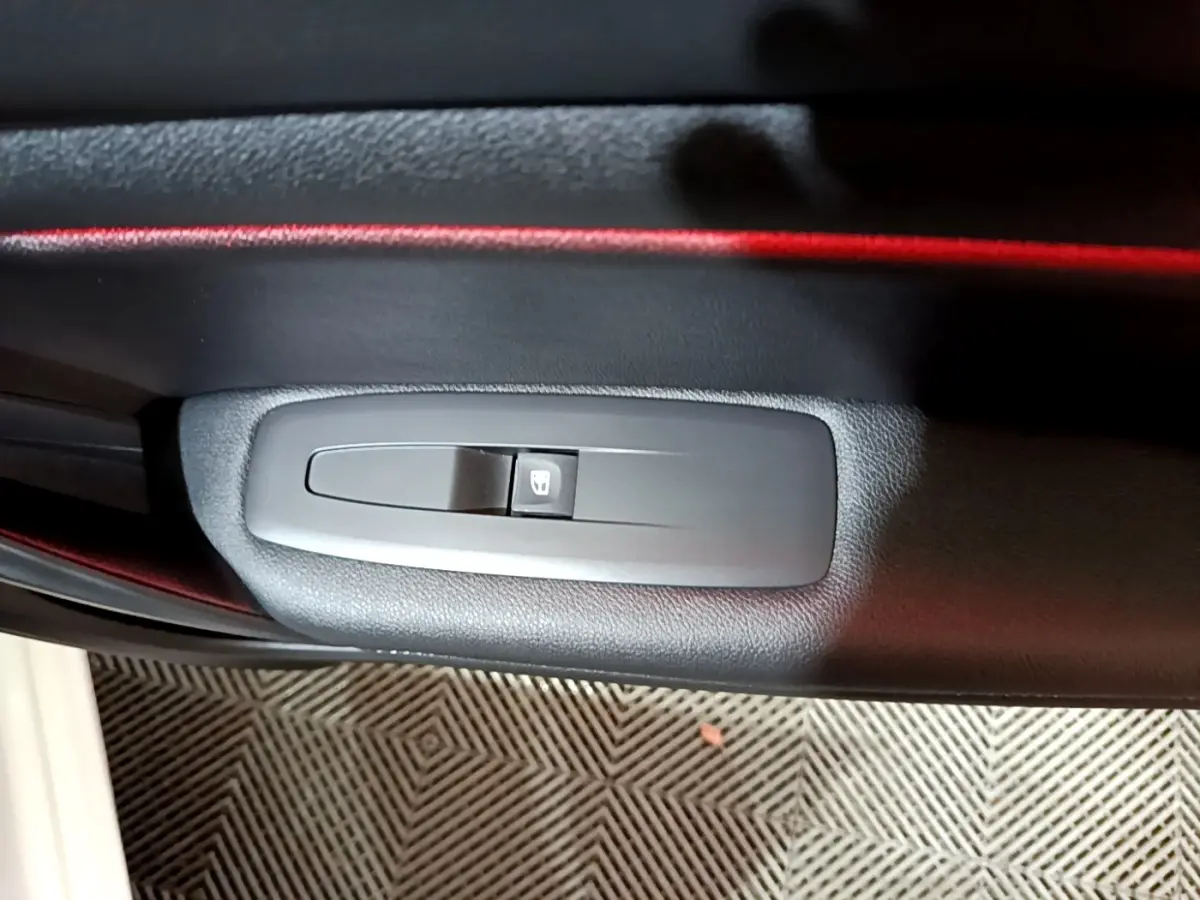 Détail du bouton de commande de lève-vitre sur la porte intérieure côté conducteur de la Renault Mégane blanche 2023.