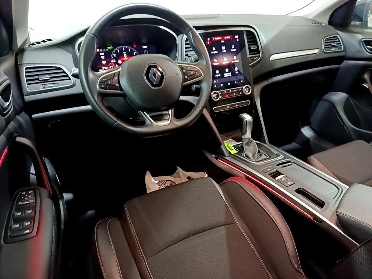 Vue intérieure avant droite de la Renault Mégane Techno TCe 140 2023, tableau de bord noir avec écran tactile vertical et éclairage d'ambiance rouge.