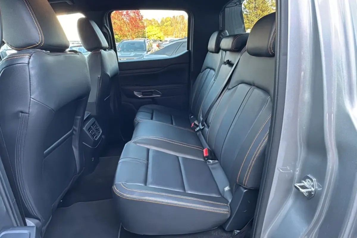 Vue intérieure arrière côté droit du Ford Ranger PHEV 281 Wildtrak gris iconic avec sièges cuir noirs et surpiqûres orange.