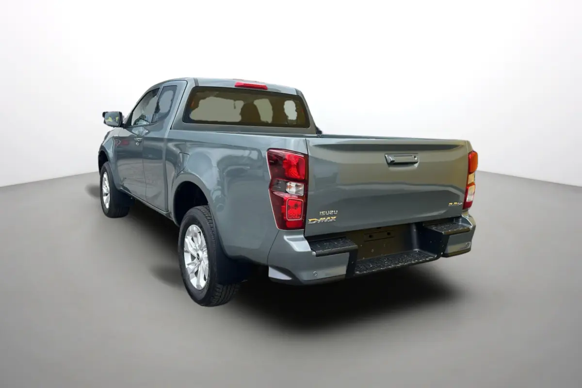 Vue 3/4 arrière gauche d'un Isuzu D-MAX 2026 gris métallisé avec benne et feux arrière rouges.