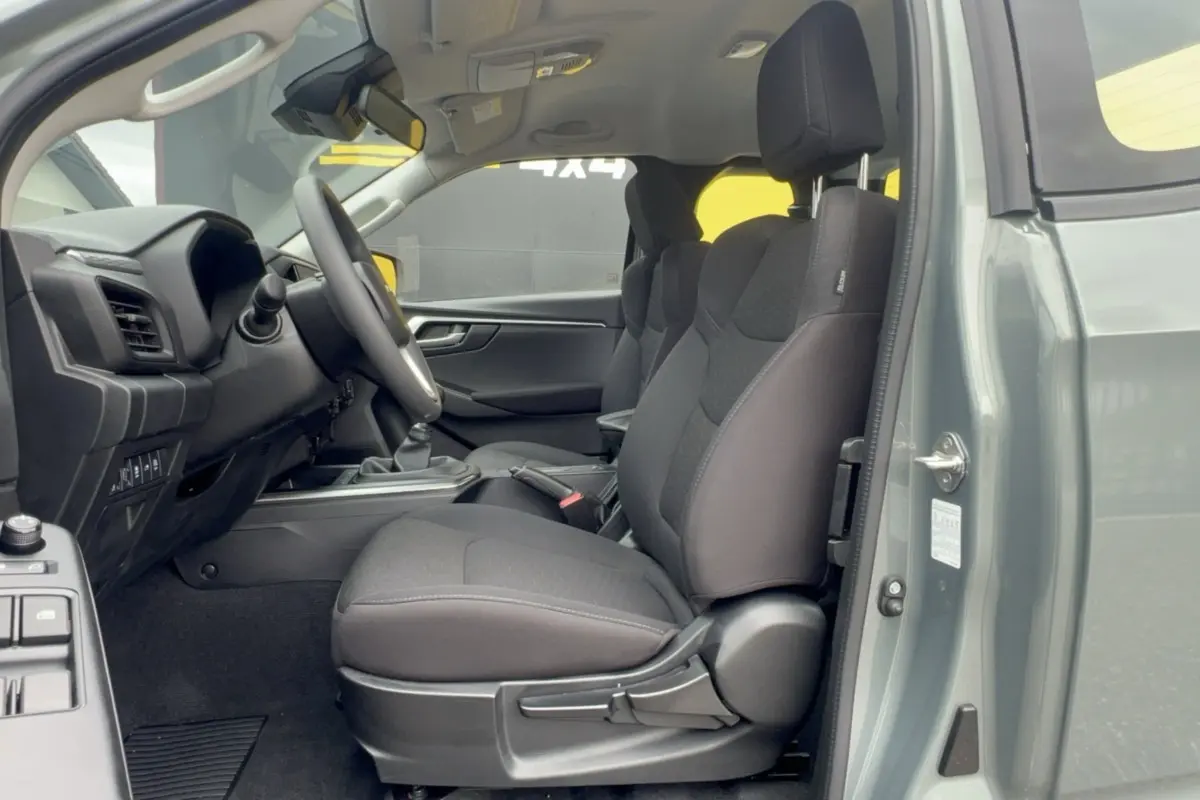 Vue intérieure côté conducteur de l'Isuzu D-MAX 2026 vert Inishmore, sièges tissu noirs et tableau de bord moderne.