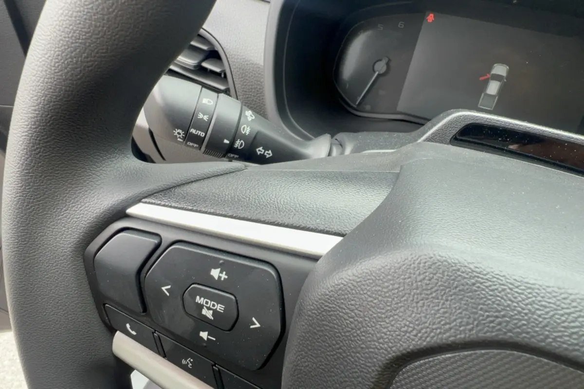 Gros plan sur le volant multifonctions noir de l'Isuzu D-MAX 2.2 TD 164 Space Evolution, avec commandes audio visibles.