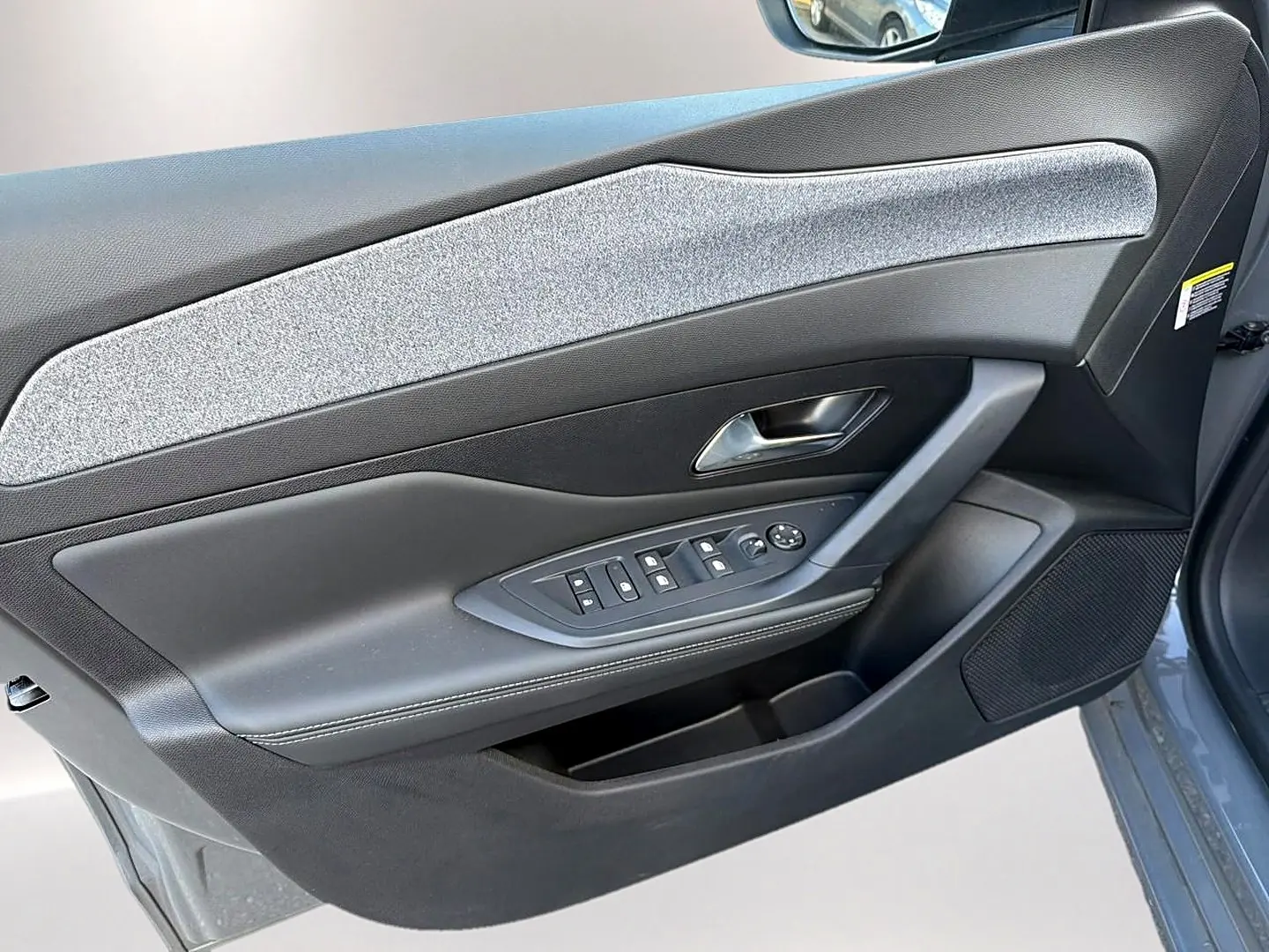 Vue rapprochée de la porte avant gauche gris selenium de la Peugeot 308 avec commandes de vitres et haut-parleur intégré.