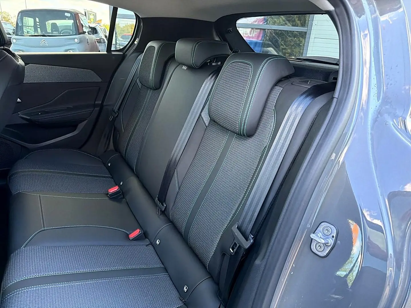 Vue intérieure sur la banquette arrière en tissu et cuir noir avec surpiqûres vertes d'une Peugeot 308 gris selenium.