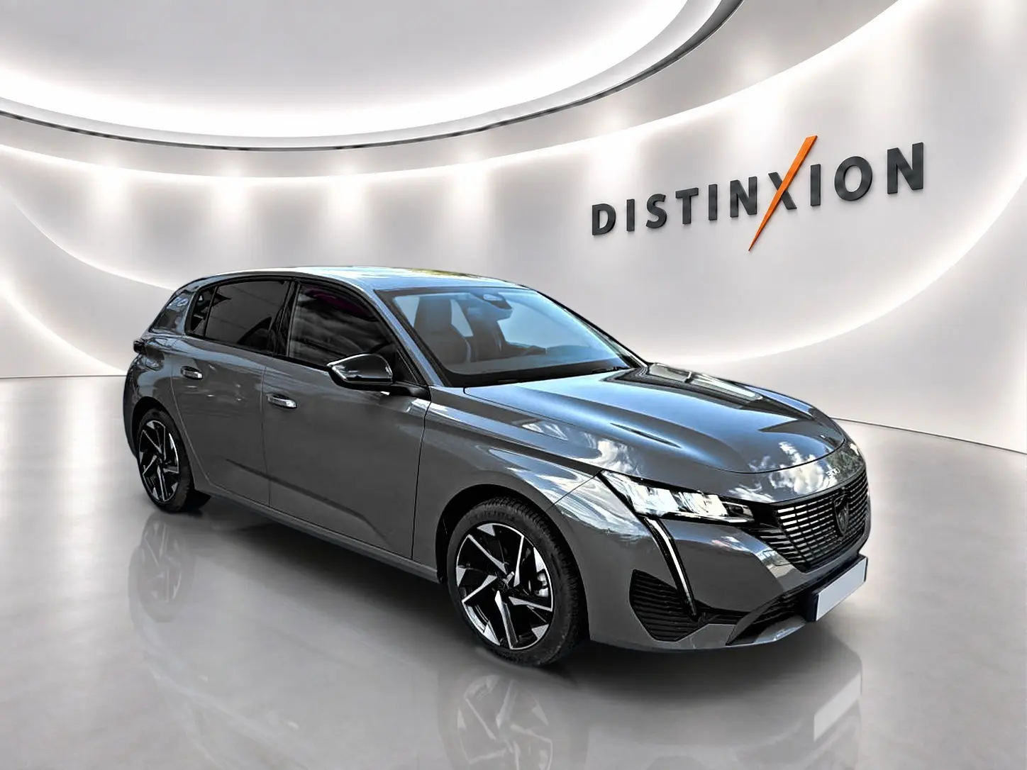 Peugeot 308 gris selenium en 3/4 avant droit, avec jantes alliage noires et phares LED distinctifs.