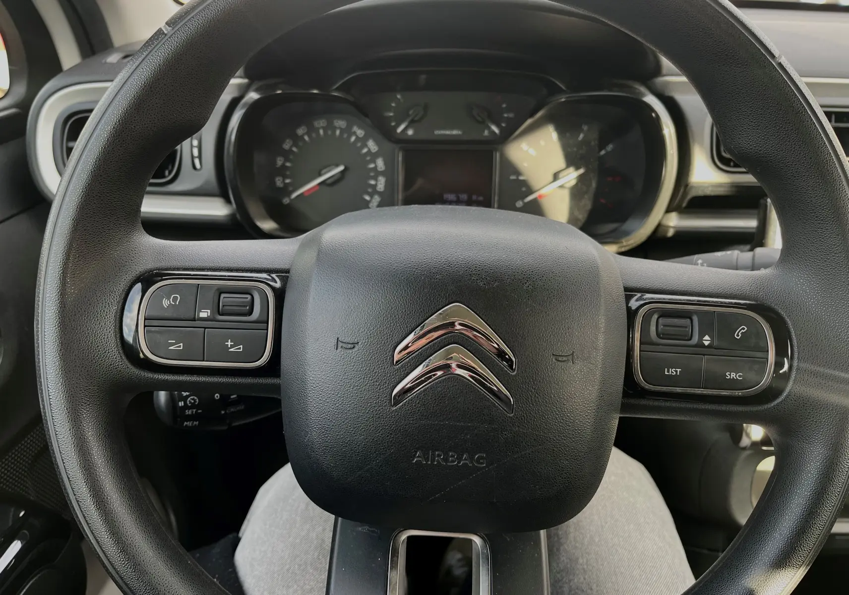 Vue rapprochée du volant noir de la Citroën C3 2019 avec commandes intégrées et tableau de bord en arrière-plan.