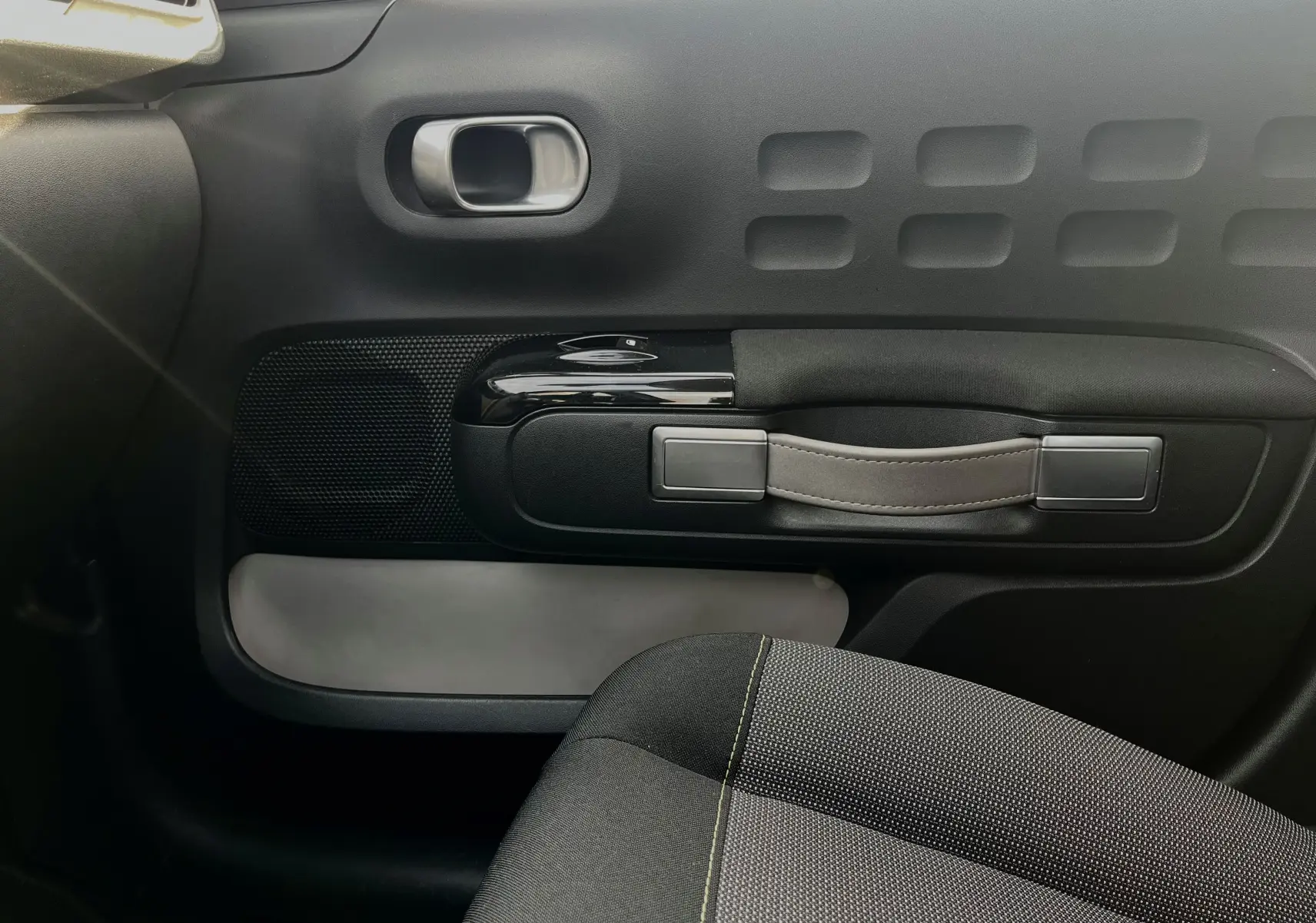 Détail de la porte intérieure côté droit d'une Citroën C3 blanche 2019, avec poignée en cuir et tissu noir du siège visible.