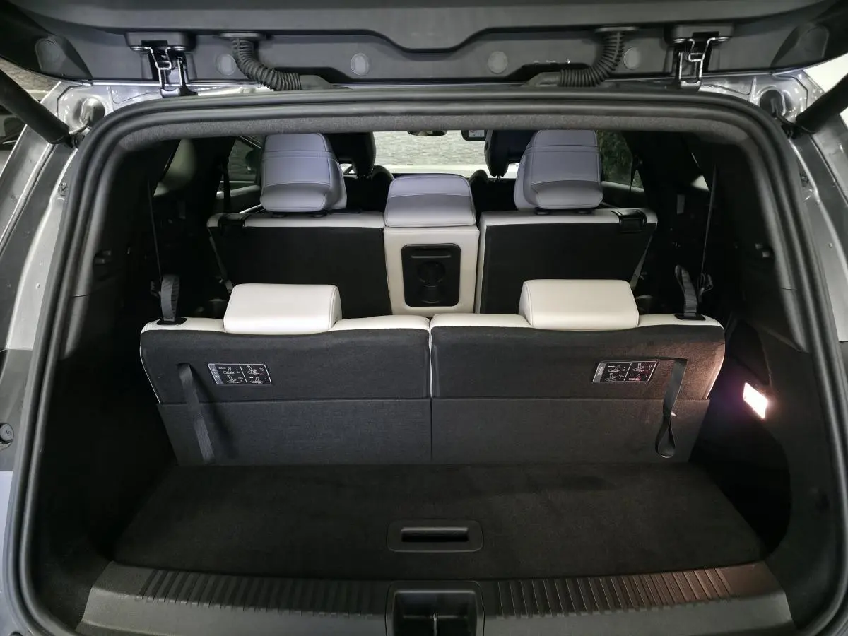 Coffre ouvert vu de l'arrière du Renault Espace gris, montrant la banquette arrière en sellerie textile claire.