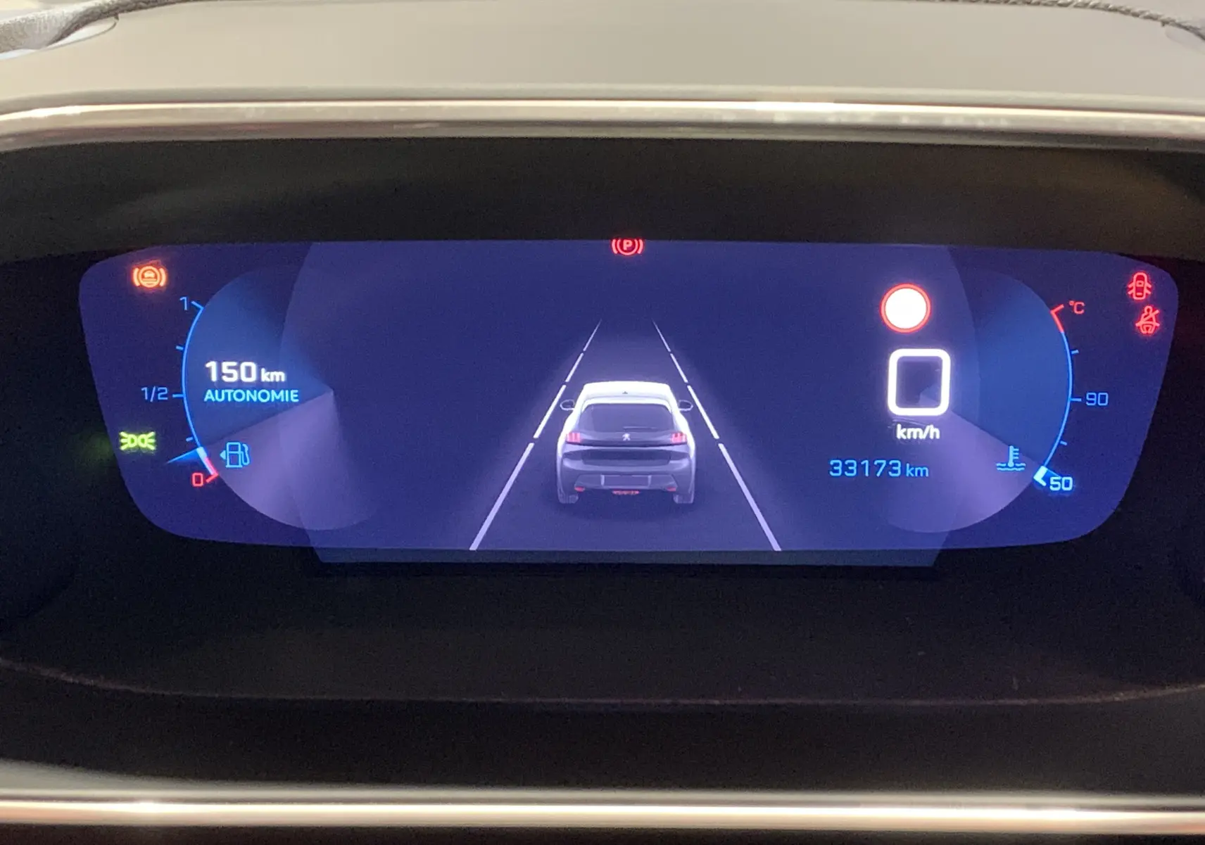 Affichage numérique du tableau de bord de la Peugeot 208 gris, montrant la vue arrière du véhicule et l'autonomie restante.