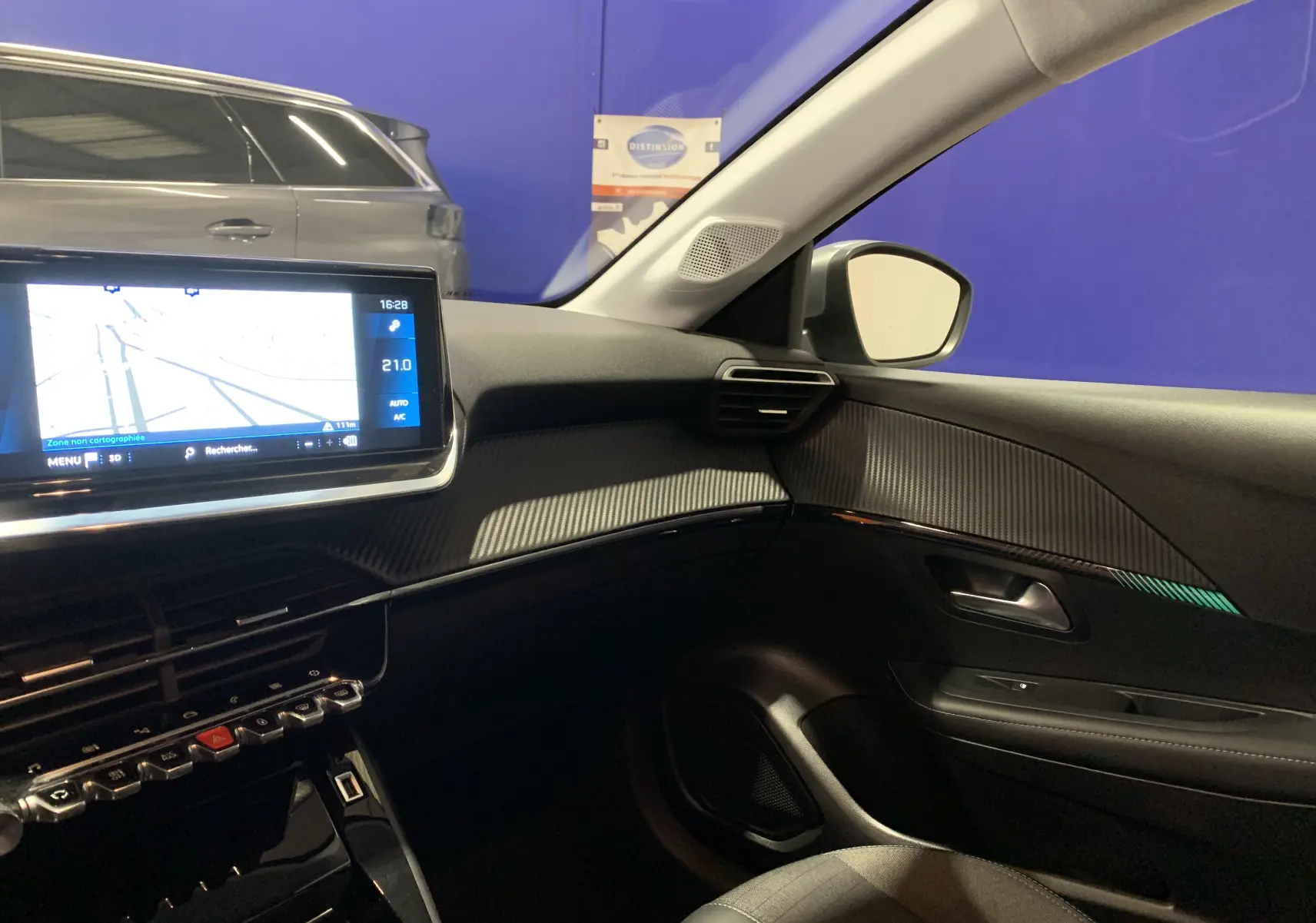 Vue intérieure côté passager de la Peugeot 208 gris, avec écran GPS tactile et tableau de bord moderne.
