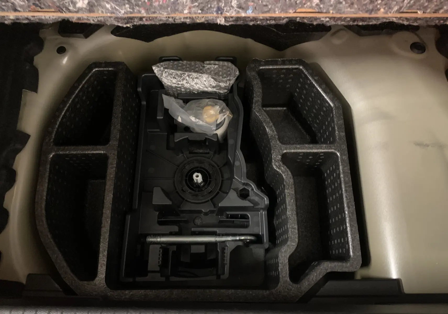 Rangement en mousse noir dans le coffre d'une Peugeot 208 gris, vue plongeante sur les compartiments vides.