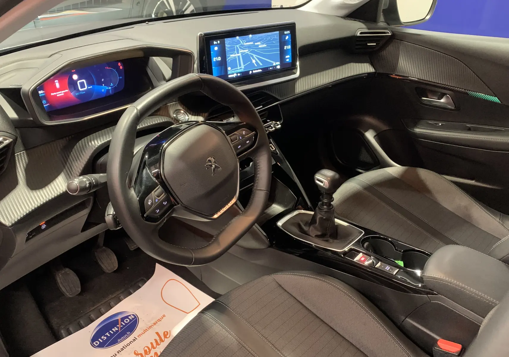 Vue intérieure côté conducteur de la Peugeot 208 PureTech 100 Allure Business gris, avec tableau de bord numérique et écran GPS tactile.