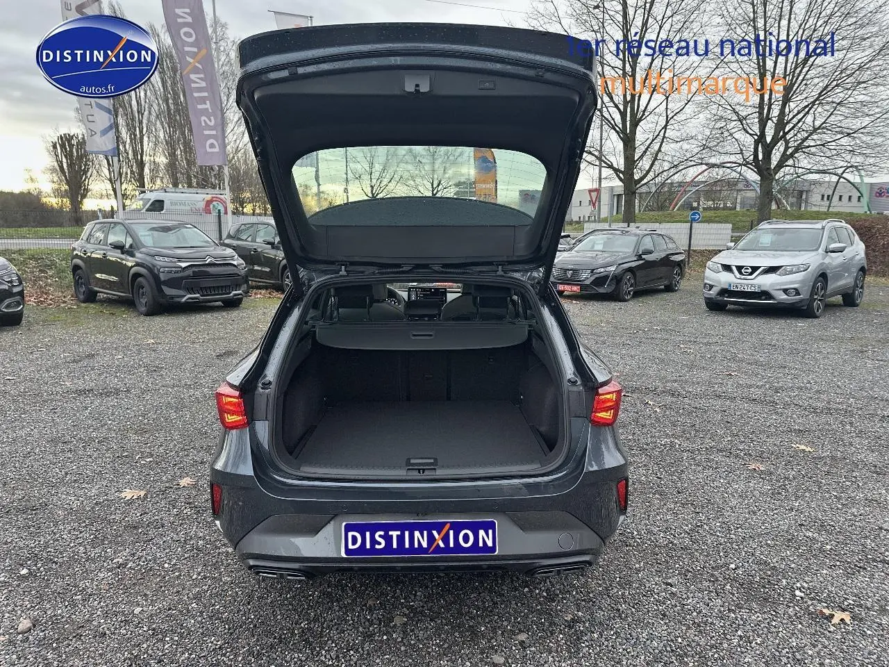 Vue arrière d'une CUPRA Leon ST gris magnétique avec coffre ouvert sur un parking extérieur.