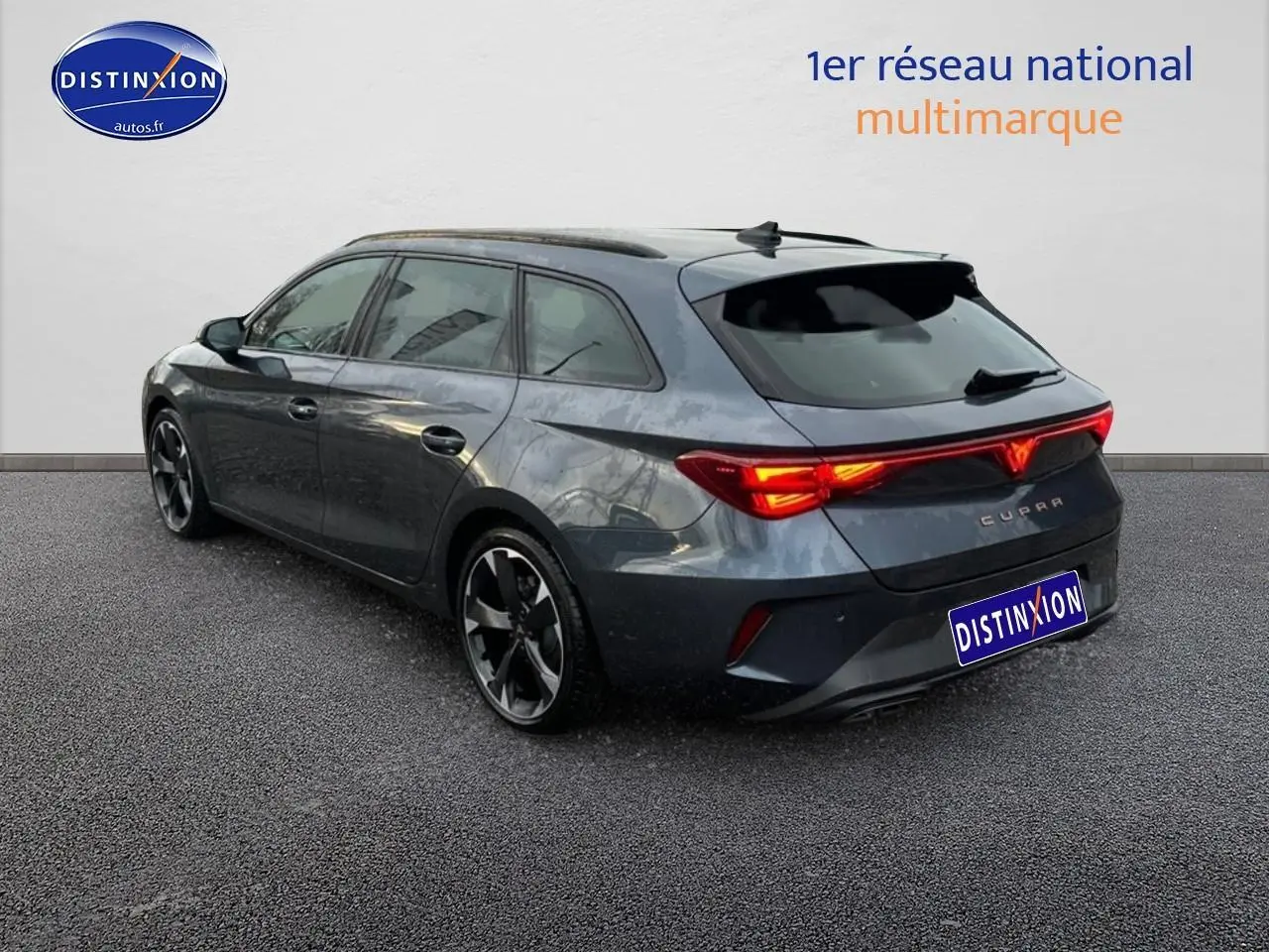 Vue 3/4 arrière droite d'une CUPRA LEON ST 2025 gris magnétique avec feux arrière LED allumés et jantes alu noires.