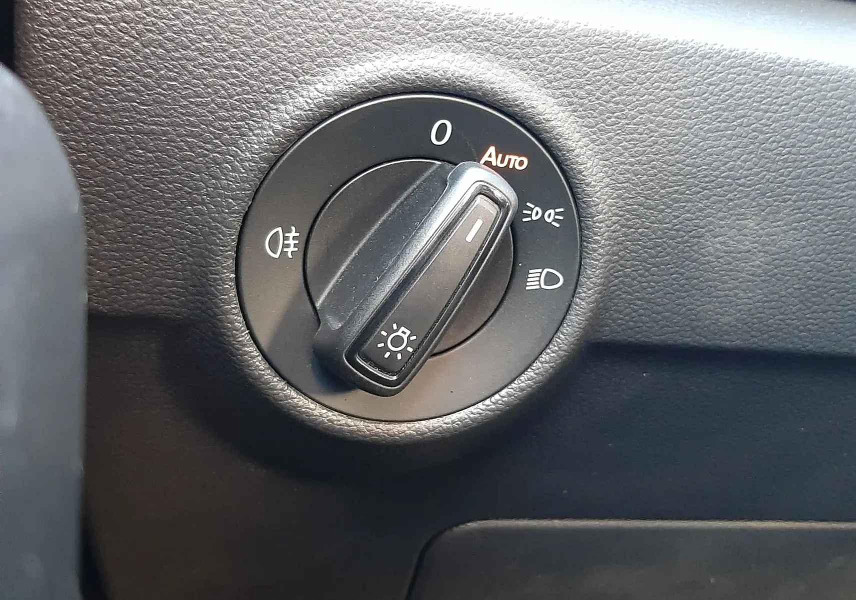 Gros plan sur le sélecteur de phares du Volkswagen T-Roc 1.5 TSI 150CH LIFE DSG7, intérieur noir texturé.